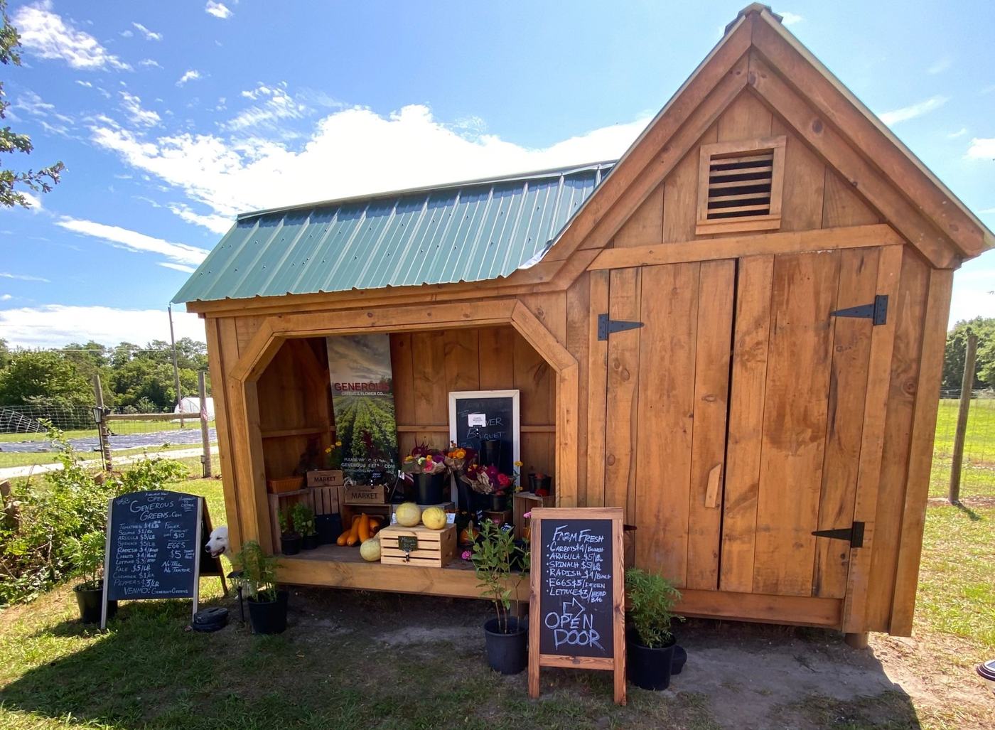 The wooden farm stand with its green roof and chalkboard price signs